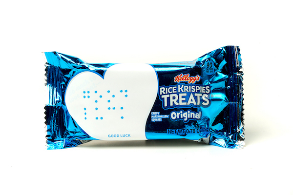 A picture of a Kellogg's Rice Krispies Treat with a heart-shaped sticker on it that says "Good Luck" in Braille.