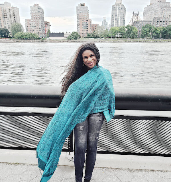 Lachi in front of East River and NYC Buildings wearing green shawl.